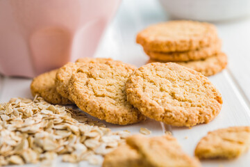 Tasty oatmeal cookies and rolled oat on white table.