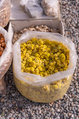 A bag of yellow corn sits on a gravel surface