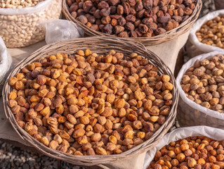 A basket full of nuts is on a table next to other baskets of nuts