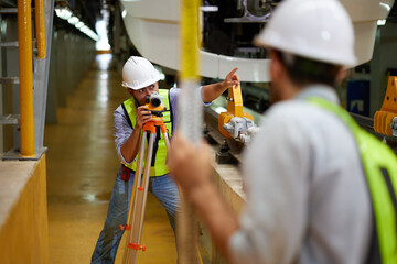 worker or engineer using theodolite surveying optical instrument for measuring at construction...