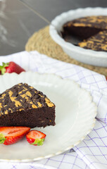 healthy desserts on plate on modern kitchen counter on plate.crumble with strawberry and almond, chocolate brownie pie and cupcakes with cranberries.vase with flowers as decor,woven placemat