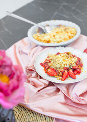 healthy desserts on plate on modern kitchen counter on plate.crumble with strawberry and almond, chocolate brownie pie and cupcakes with cranberries.vase with flowers as decor,woven placemat