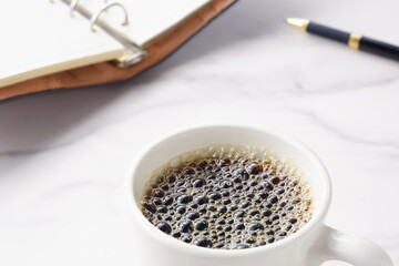 淹れたてのコーヒーを飲みながら、リング式のシステム手帳を開いて、仕事の段取りを考えているイメージ
