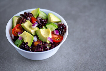 Healthy salad of fresh vegetables in a plate on a gray background.
