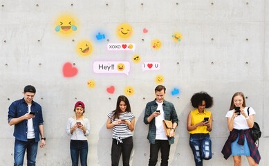 Group of young adults outdoors using smartphones together and chilling