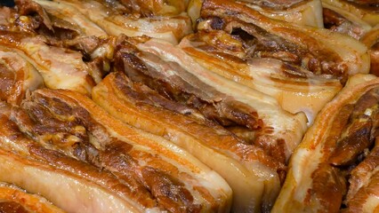 Cooked pork ribs are meticulously arranged on a perforated surface, signifying the culinary process in an industrial kitchen.