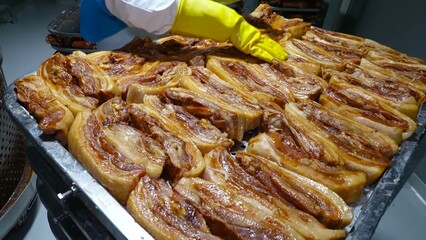 Cooked pork ribs are meticulously arranged on a perforated surface, signifying the culinary process in an industrial kitchen.