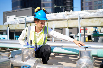 Technician checking pipeline valves or water tank area at urban industrial site