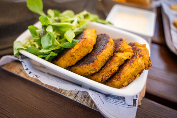 Delicious lamb's lettuce, cauliflower pancakes, and tartare on a rustic wooden board in Czech bistro