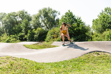 Young brunette girl pushing on a ramp at a skate park. Fun outdoor activities and active lifestyle concept. Girl in action on a skateboard.