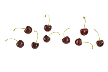 Ripe red cherries with green stems on a white background