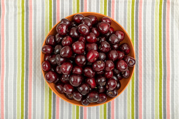 Red cherries in a bowl on a striped towel