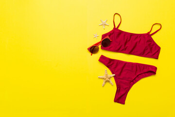 Fototapeta premium Traveler accessories, women summer bikini set swimsuit on table background with empty space for text. Travel vacation concept. Flat lay, top view Female sexy swimwear