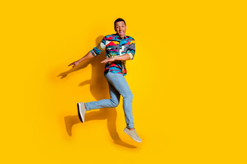 Fototapeta na wymiar Full body photo of attractive young man running hurry have fun dressed stylish colorful clothes isolated on yellow color background