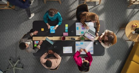 Top Down View: Diverse and Creative Colleagues Working Together At The Conference Table In Stylish Office. Male And Female Business People Using Tablets, and Laptops To Analyze Business Data On Charts - Powered by Adobe