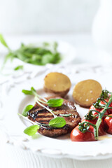 Grilled pork steak with vegetables. White wooden background. Close up. Copy space.