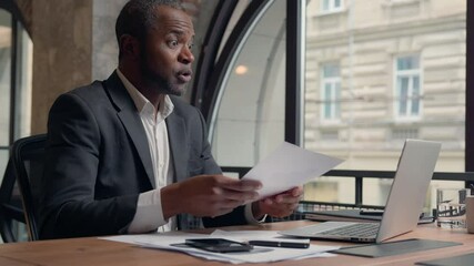 Talking African American man business employer company CEO presentation virtual negotiation talk laptop computer video conference call showing stats diagram data papers businessman guy male in office - Powered by Adobe