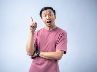 A man in a pink shirt looks excitedly upwards with his index finger raised, as if having an idea....