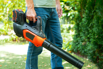 Cordless Leaf Blowers. handheld, cordless, electric leaf blower in a garden, selective focus....