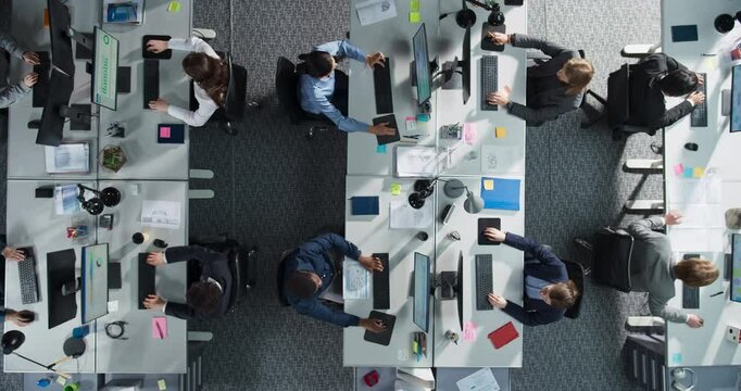 Top Down View Of Diverse Colleagues Working In Corporate Office Of Hedge Fund. Using Desktop Computers, Discussing Documents, Analyzing Data. Concept Of Teamwork And Professional Business Environment.