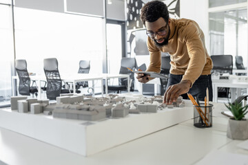 Young man in casual clothes working on miniature and looking involved