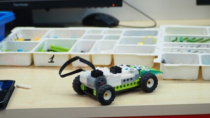a girl controls a car assembled from a construction set from a tablet. The robot from the children's designer on the control panel. DIY educational toy. A radio-controlled robot rides on the floor
