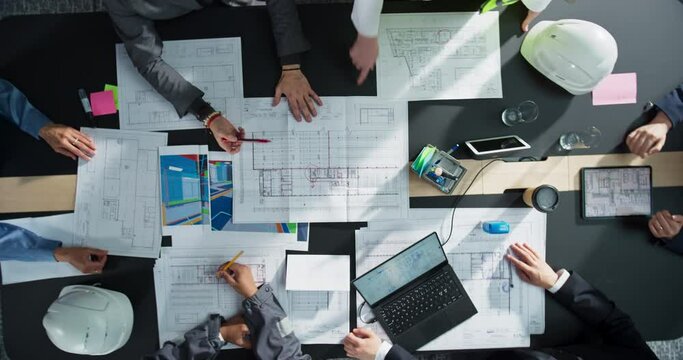 Top Down View Zoom Out: Diverse Engineers, Managers, Construction Coordinators Gathered Around The Table to Discuss Real Estate Project Blueprints Or Architectural Plan, Using Laptop, Tablet In Office
