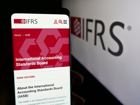 Stuttgart, Germany - 06-26-2024: Person holding cellphone with webpage of International Financial Reporting Standards Foundation (IFRS). Focus on center of phone display.