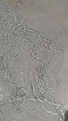 Trendy summer nature banner. Defocused liquid clear water surface texture with splashes bubbles with copy space. Water waves in sunlight background.	
