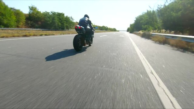 Follow to motorcyclist riding on modern sport motorbike at highway. Biker racing his motorcycle on country road. Guy driving bike during trip. Concept of freedom and adventure at journey. Aerial shot