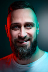 Obraz premium Studio portrait with colorful light of young handsome bearded man.