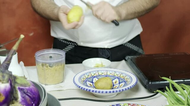 Peeling boiled potation for the preparation of Cotoletta, a signature dish of Milan