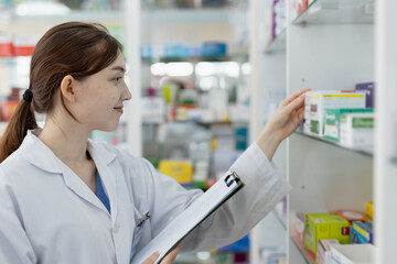 woman pharmacists working are select medications on shelf in drug store. Drug seller medicine check for information assortment of products in pharmacy.