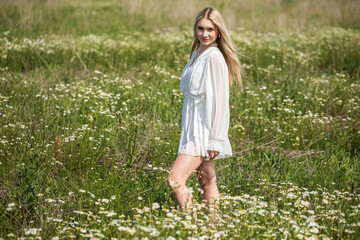 Portrait of a young beautiful blonde in a chamomile field