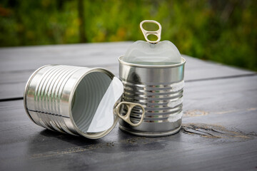 Twp empty and opened cans on wooden table