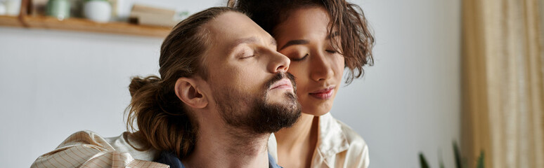 A couple lovingly embraces at home, eyes closed, enjoying a moment of peace.