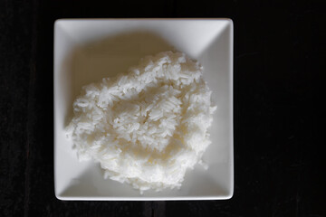 A white square bowl with a serving of jasmine rice in the shape of a heart.