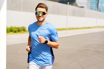 A vibrant athlete in blue sportswear, smiling and jogging energetically along an urban path under a bright sky.