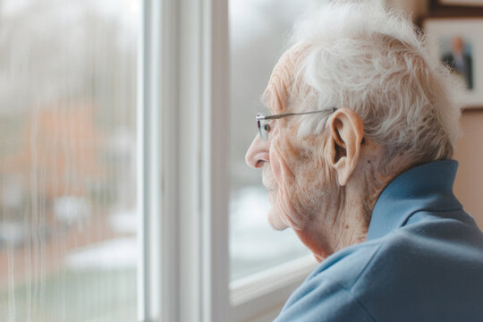 Elderly man looking out window on cloudy day, World Alzheimer's Month concept - Powered by Adobe