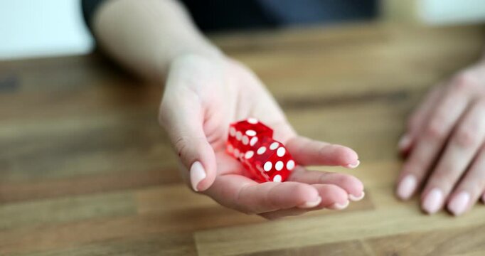 Female hand shaking red game cubes over table closeup 4k movie slow motion. Gambling addiction and luck concept
