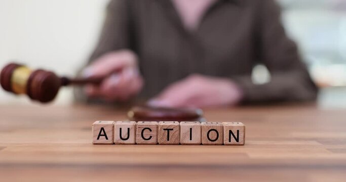 Word Auction from cubes on table against auctioneer with gavel