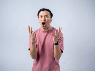 Asian man in a pink t-shirt, standing against a plain background, with an expression of surprise...