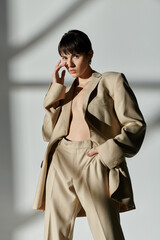 A woman wearing a beige suit poses against a white backdrop.
