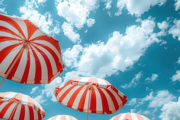 Three red and white striped umbrellas are open on a sunny day