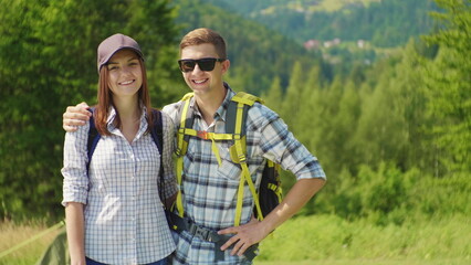 Couple of young happy tourists with backpacks. They look at the camera and smile.
