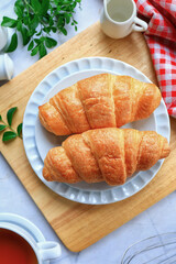Two croissant in white plate with hot tea for morning breakfast or afternoon tea time, top view food table