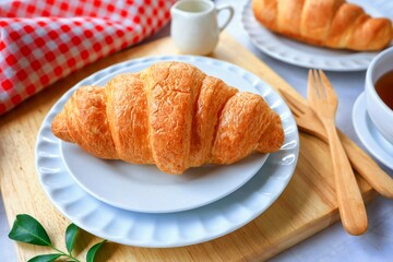 Two croissant in white plate with hot tea for morning breakfast or afternoon tea time