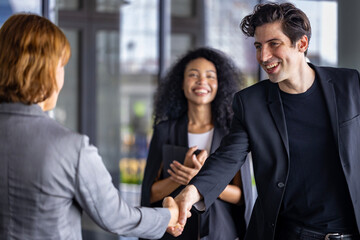 Team of diversity business people having agreement and handshake deal over new strategic strategy project on investment real estate with recognition and applause from other colleagues for partnership