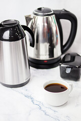 mesa de porcelanato marmore branca com cinza com garrafa de café inox, chaleira inox, açucareiro inox e xícara de café com café de porcelana branca