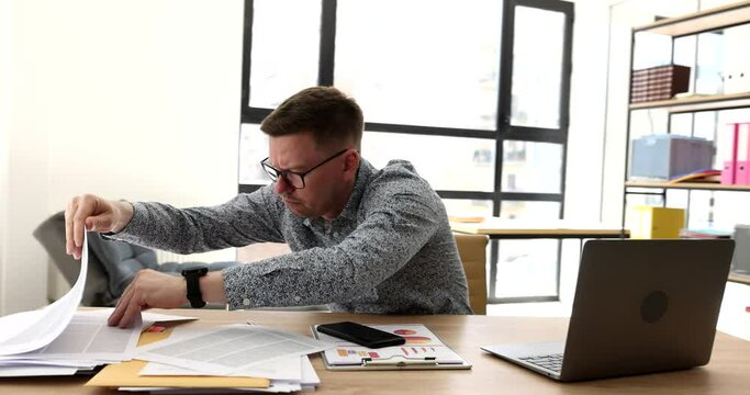 Businessman in glasses looking for document at table in office 4k movie. Difficulties and problems in paperwork concept